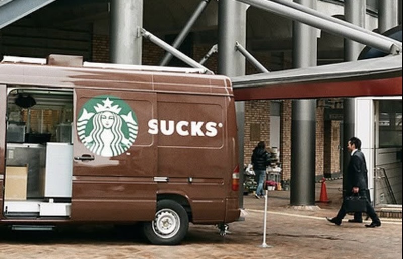 A Starbucks van is parked with the door slid open. The logo now reads S-UCKS.